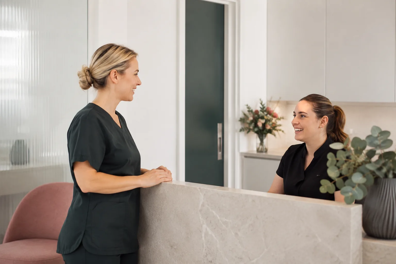 A dentist speaking with a receptionist in a bright neighbourhood practice
